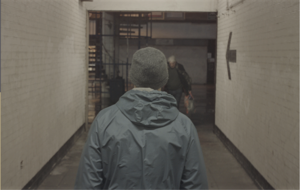 Hooded figure walking down a corridor, still from I Am Super
